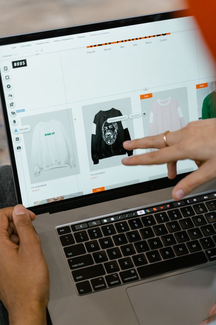 Gros plan sur des mains interagissant avec un site de shopping sur l’écran d’un ordinateur portable, à l’intérieur.